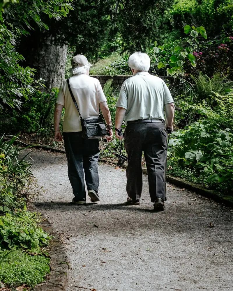 Older couple walking side by side along a garden path